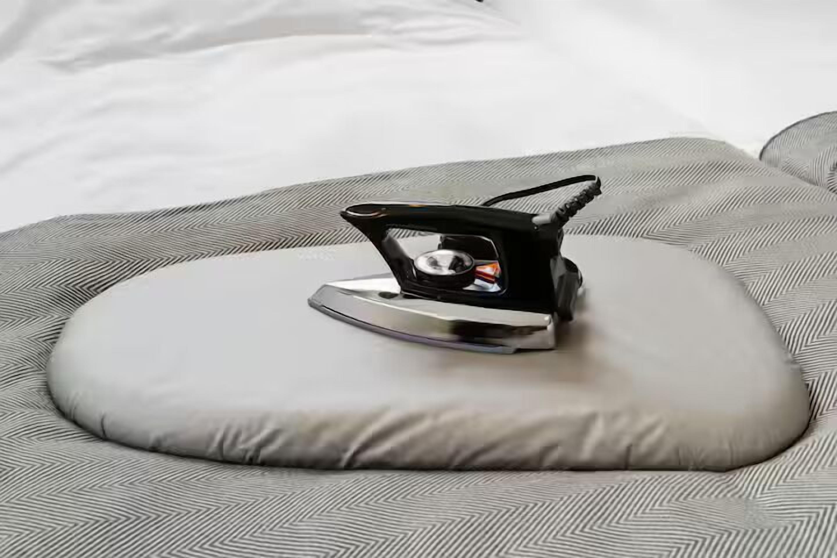 A bed with a gray patterned bedspread and a gray pillow.