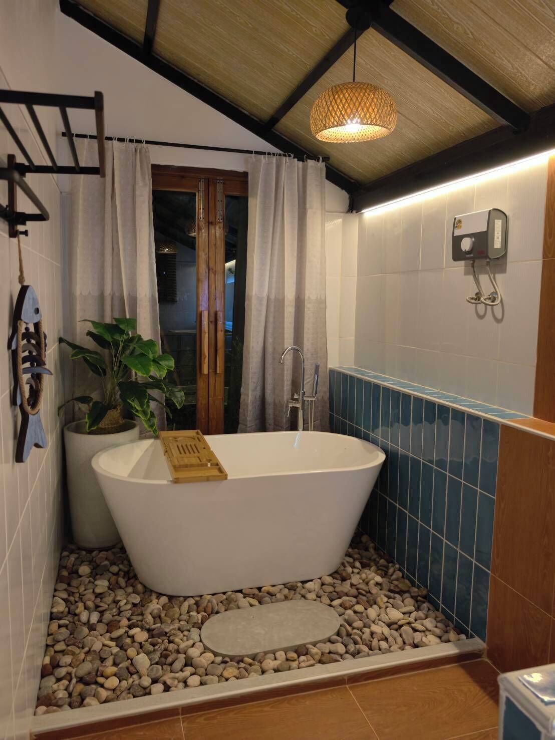 A bathroom with a freestanding bathtub, a potted plant, a shower, and a towel rack.