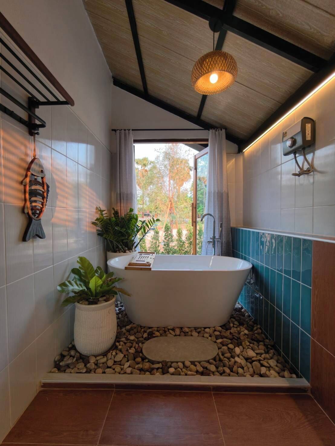 A modern bathroom with a freestanding bathtub, a fish-shaped decoration, and a view through a window.