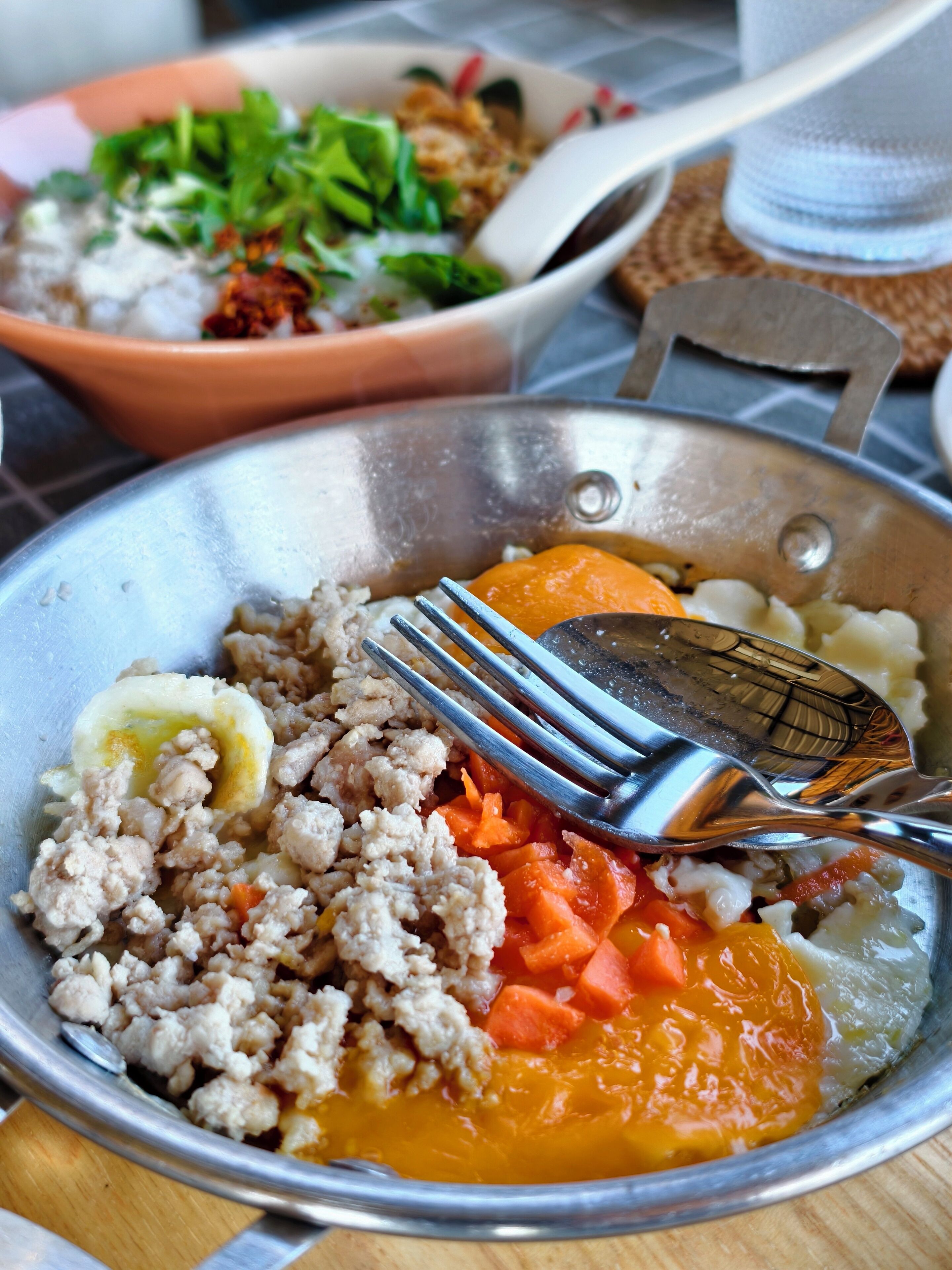 Un plat composé de viande hachée, de carottes et d’un œuf dur, servi dans un bol en métal.