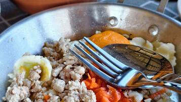 Un plat composé de viande hachée, de carottes et d’un œuf dur, servi dans un bol en métal.