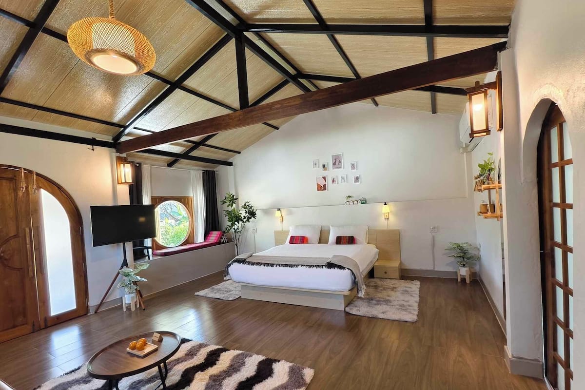 A spacious bedroom with a large bed, a television, and a window with a view.