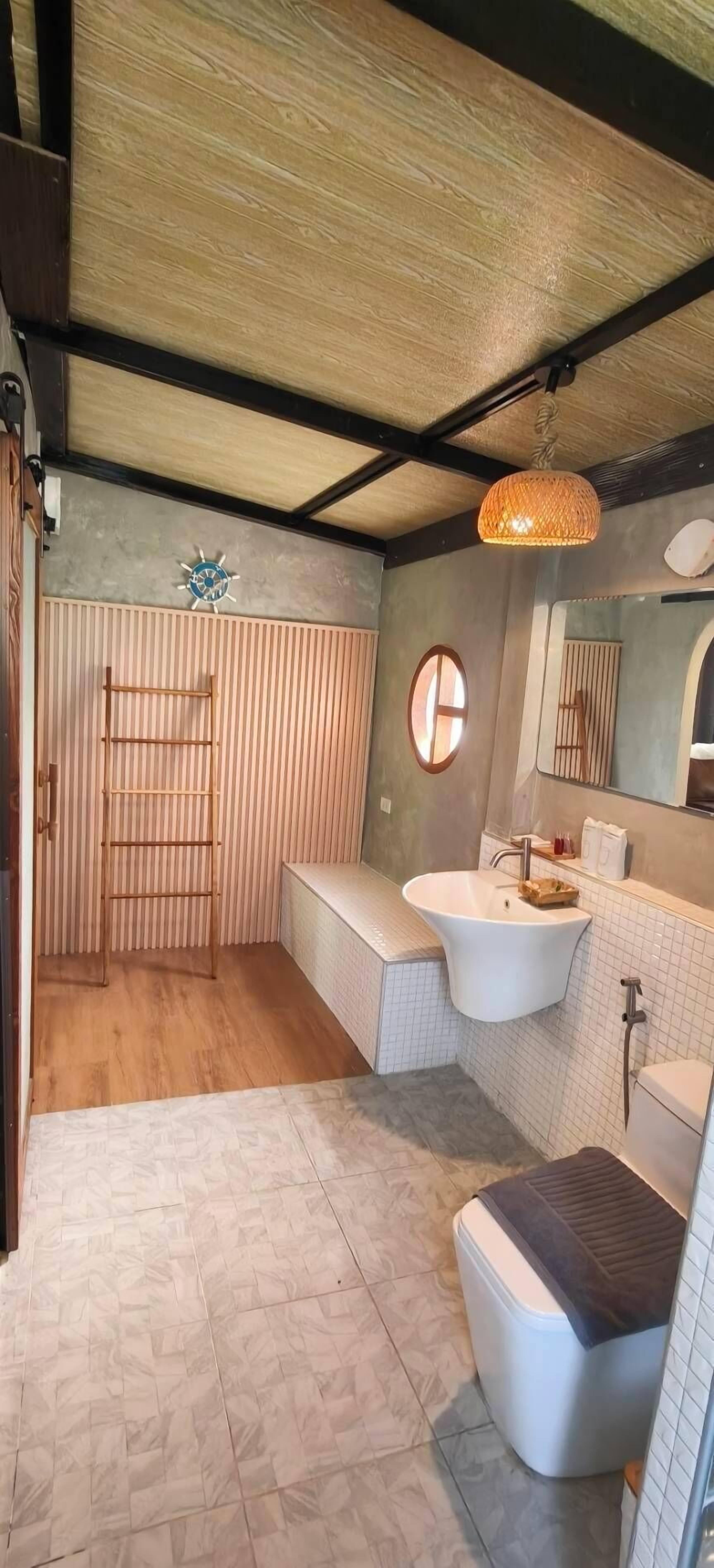Une salle de bain avec un plancher en bois, une baignoire sur pieds, un lavabo avec un miroir et un porte-serviettes.