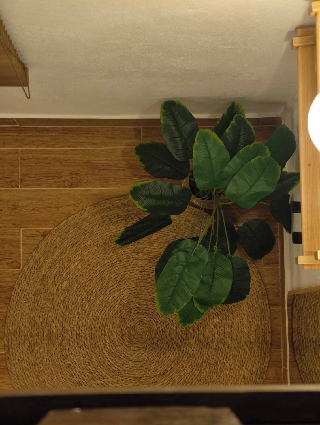 A room with a woven round table, a staircase, and a wooden wall.