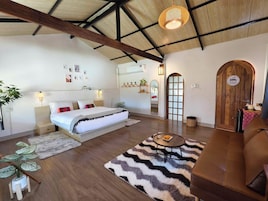 Una habitación amplia con una cama, un sofá, una mesa de comedor y un gran arco.