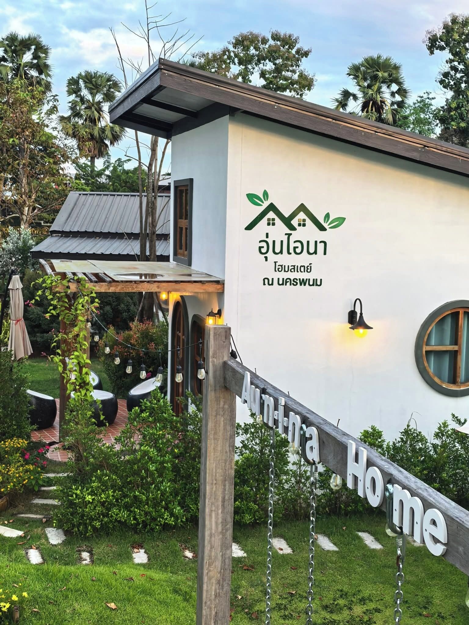 Una casa moderna con un letrero que dice "Aun-na Home" y un logotipo con hojas verdes y una casa.