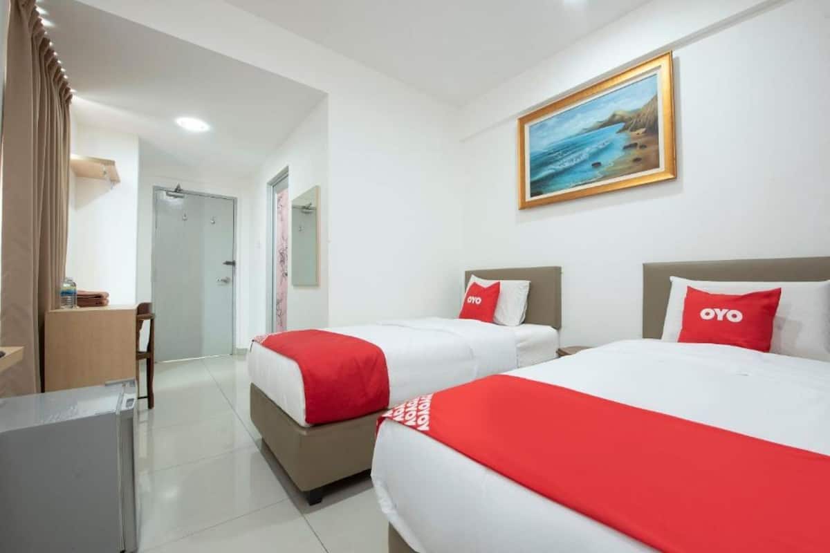 Una habitación de hotel con dos camas, un escritorio, una silla y un cuadro en la pared.