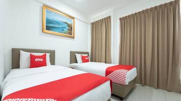 Habitación de hotel con dos camas, cortinas color beige, un cuadro de una playa y una colcha de cama rojo y blanco.