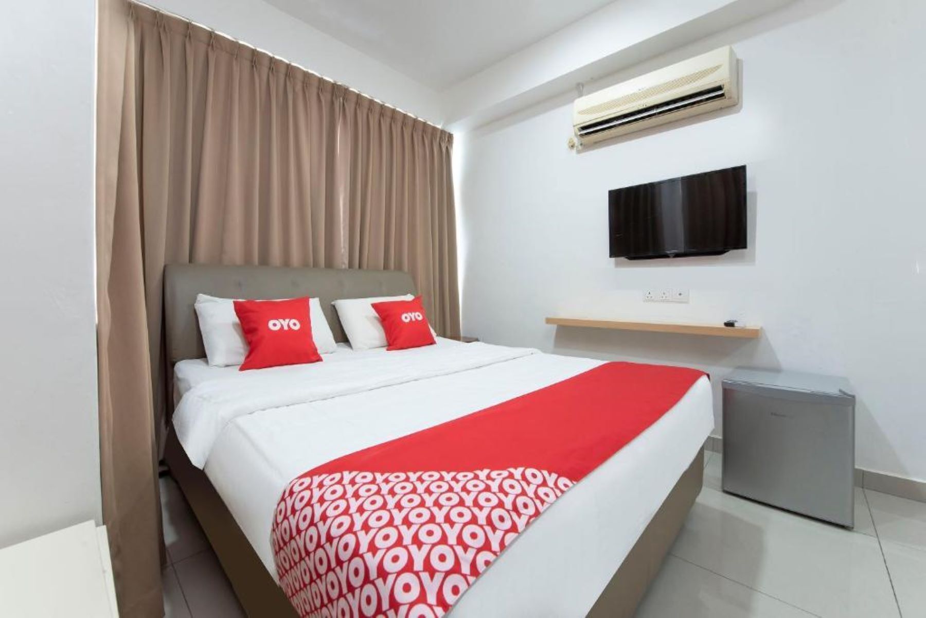 Una habitación de hotel con cama, televisión montada en la pared, aire acondicionado y un mueble pequeño.