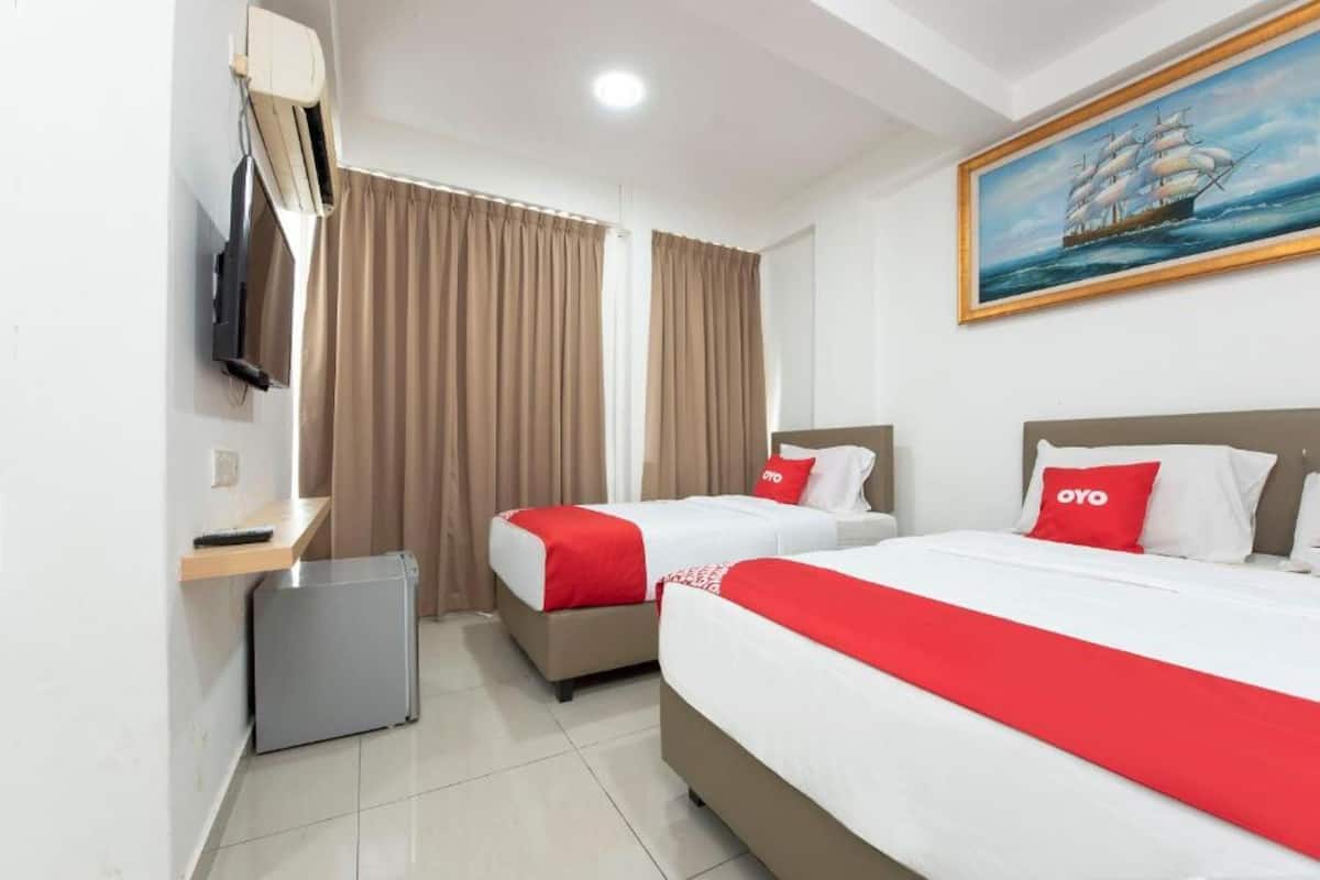 Habitación de hotel con dos camas, un televisor, un cuadro de barco y un pequeño escritorio con lámpara.