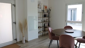 A dining area with a round table, four chairs, a bookshelf, and a door.