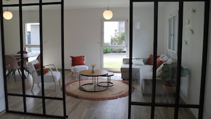 A modern living room with a round table, white sofas, and a large window.