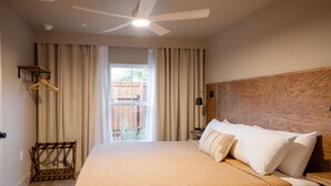 A hotel room with a bed, a ceiling fan, a window with curtains, and a wooden headboard. - Gloria Inn Unit 3- 5 minutes from Baylor and 2 Blocks to Magnolia (Waco)