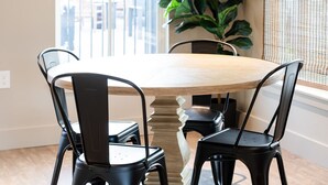 A dining area with a round table, four chairs, a potted plant, and a window with blinds. - Gloria Inn Unit 3- 5 minutes from Baylor and 2 Blocks to Magnolia (Waco)