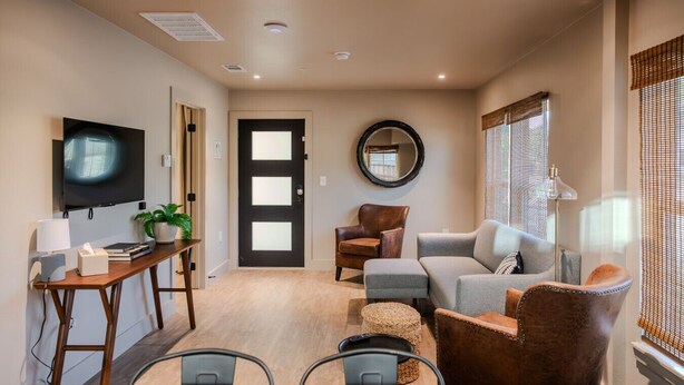 A modern living room with a sofa, armchairs, a coffee table, a TV, and a dining area with a table and chairs. - Gloria Inn Unit 5 -5 minutes from Baylor and 2 Blocks to Magnolia (Waco)