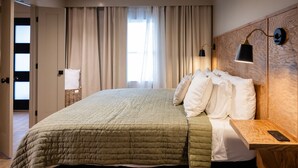 Une chambre d’hôtel avec un lit, des rideaux, une lampe de chevet, une table de chevet et un téléphone fixé au mur.