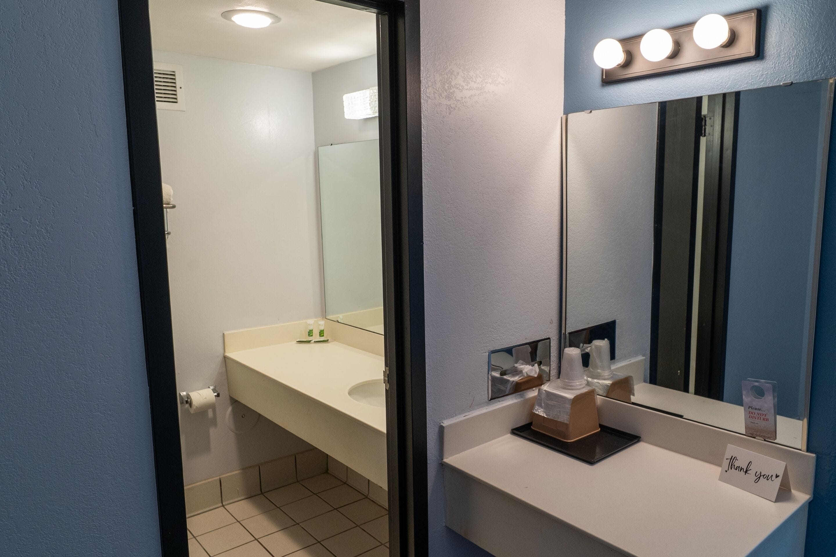 A bathroom with a white sink, mirror, and lights above the mirror.