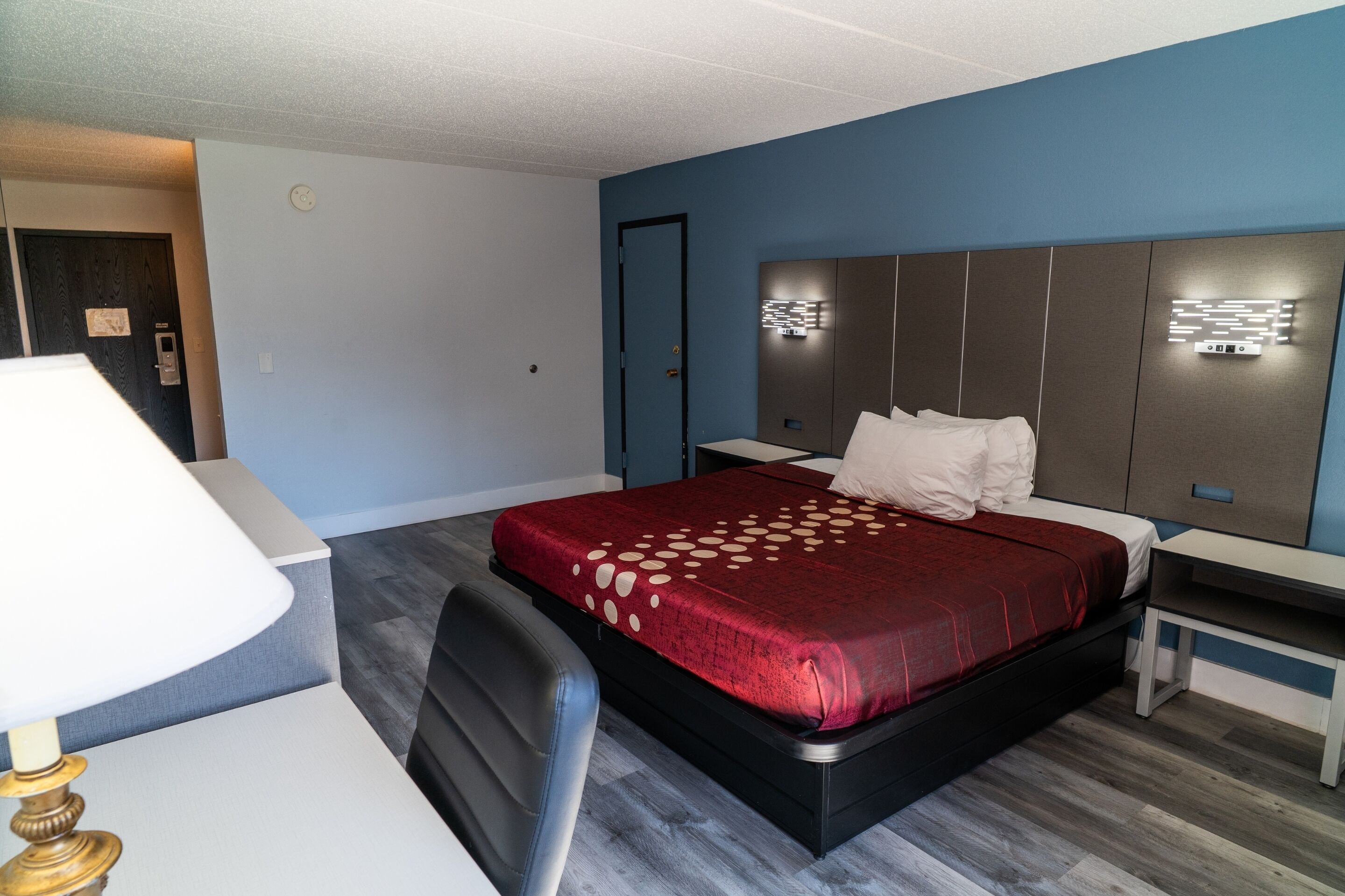 A hotel room with a bed, bedside tables, a desk, and a chair.