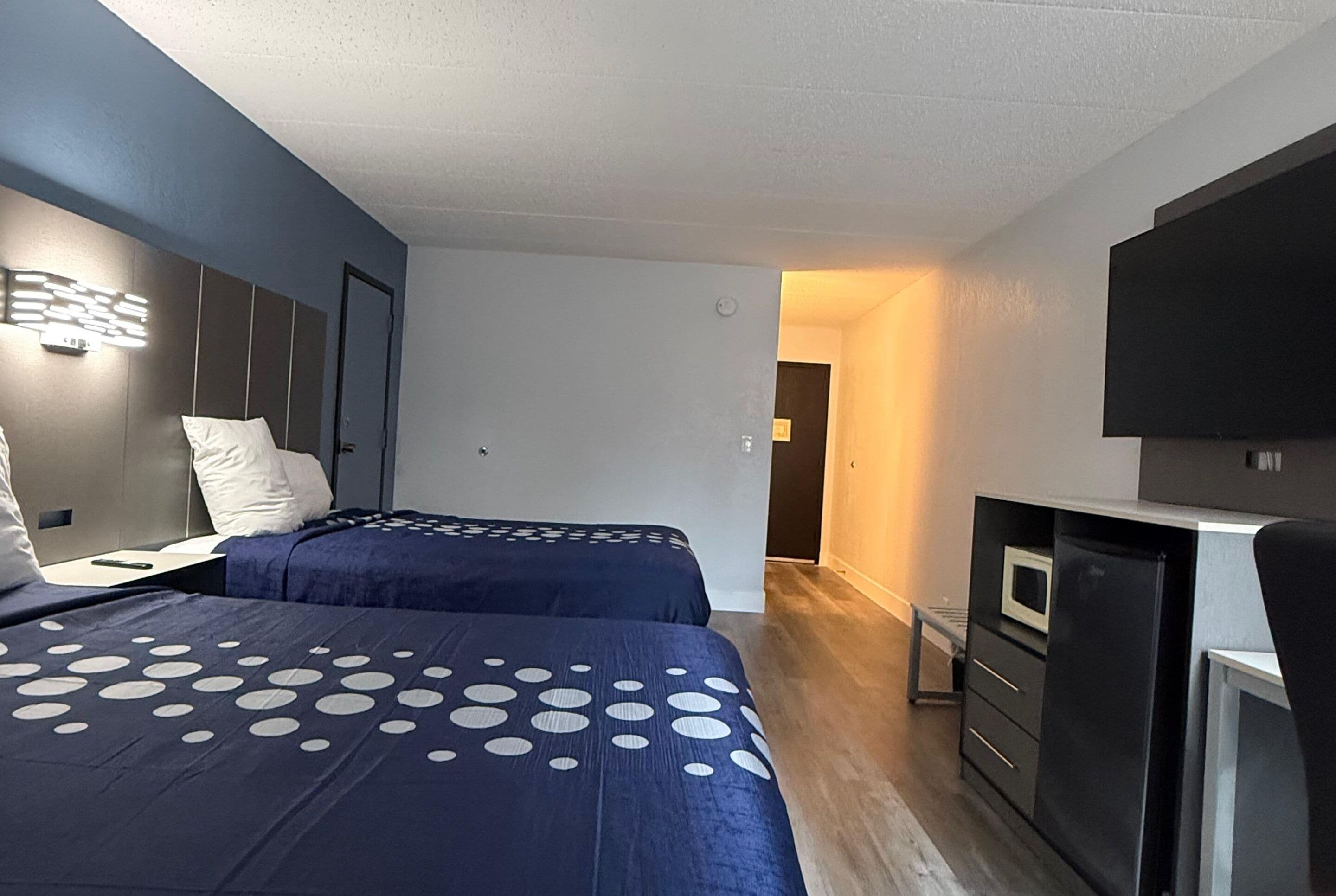 Habitación de hotel con dos camas, un escritorio, un microondas y un televisor.