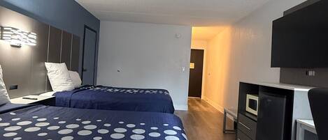 Habitación de hotel con dos camas, un escritorio, un microondas y un televisor.