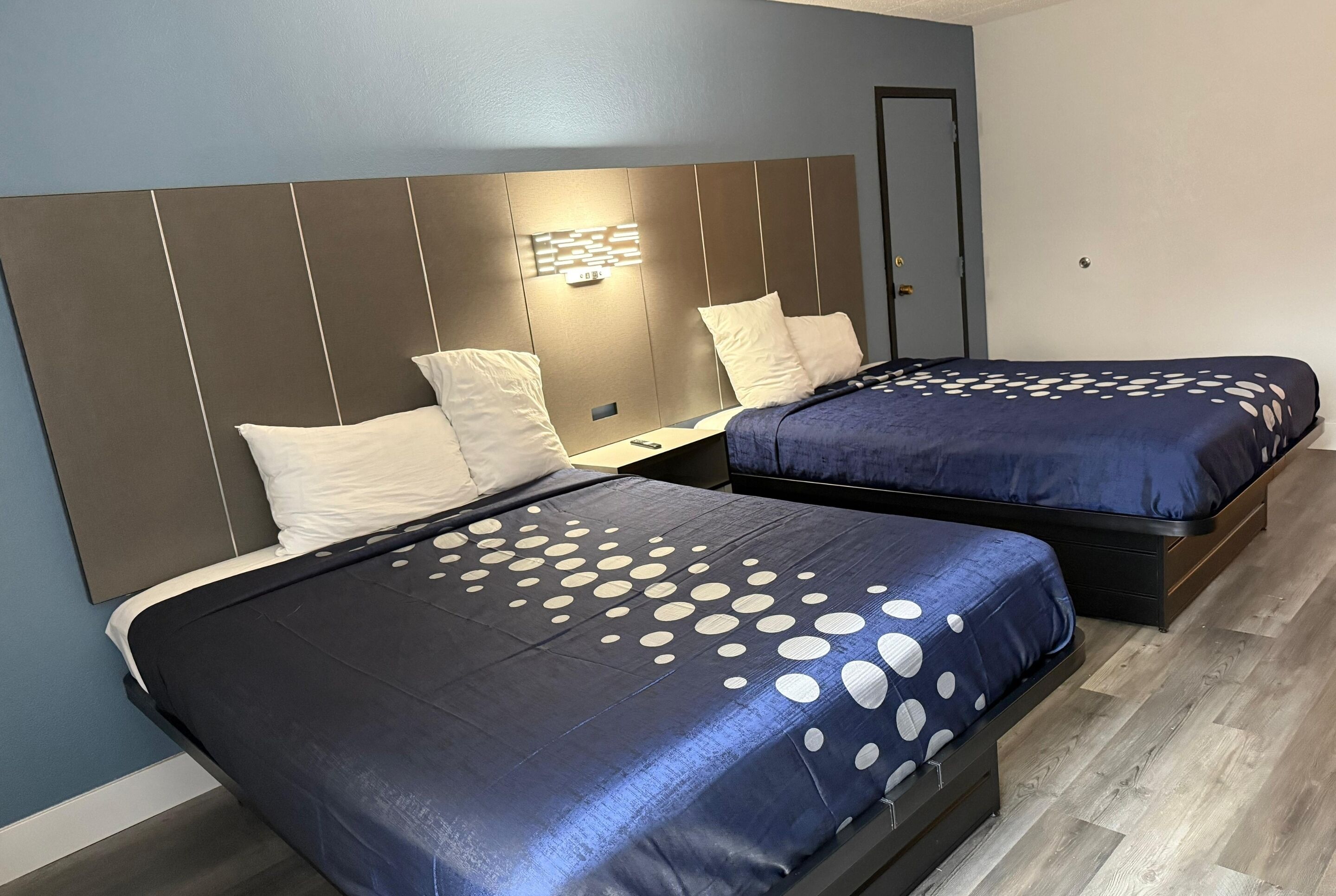 A room with two beds, each with a headboard and a bedside table.