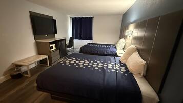 A hotel room with a bed, a TV, a desk, and a chair.