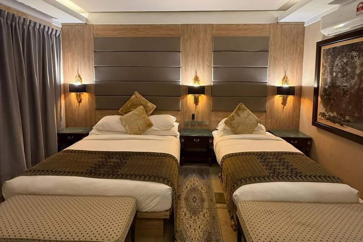 Ein Hotelzimmer mit zwei Betten, einem großen Teppich und Wandleuchten.