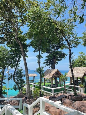 A tropical resort with thatched-roof structures, a pool, and a view of the ocean. - Sharilla Blue Star Resort (Pulau Perhentian Kecil)