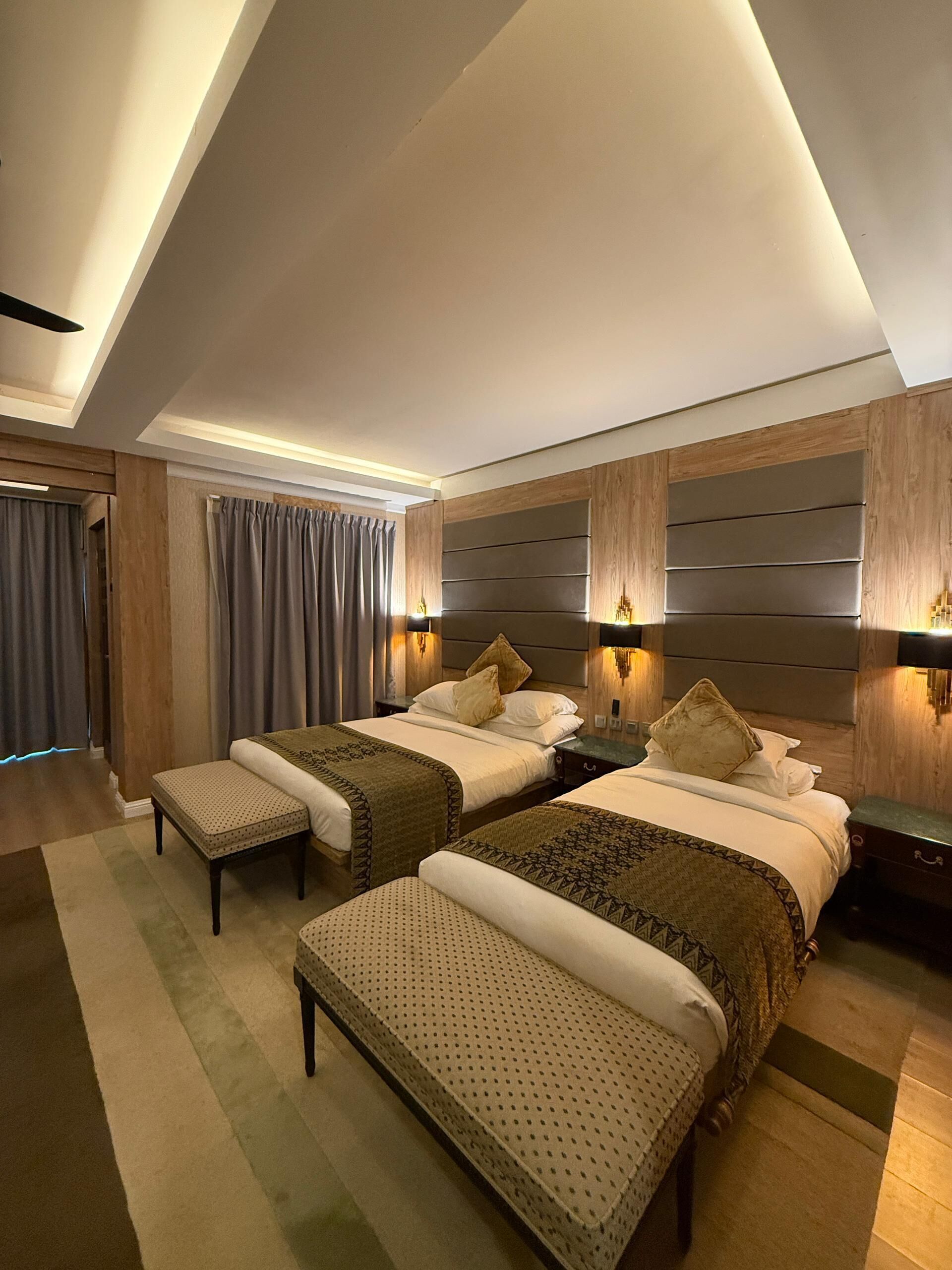A modern hotel room with two beds, a wooden headboard, and a skylight.