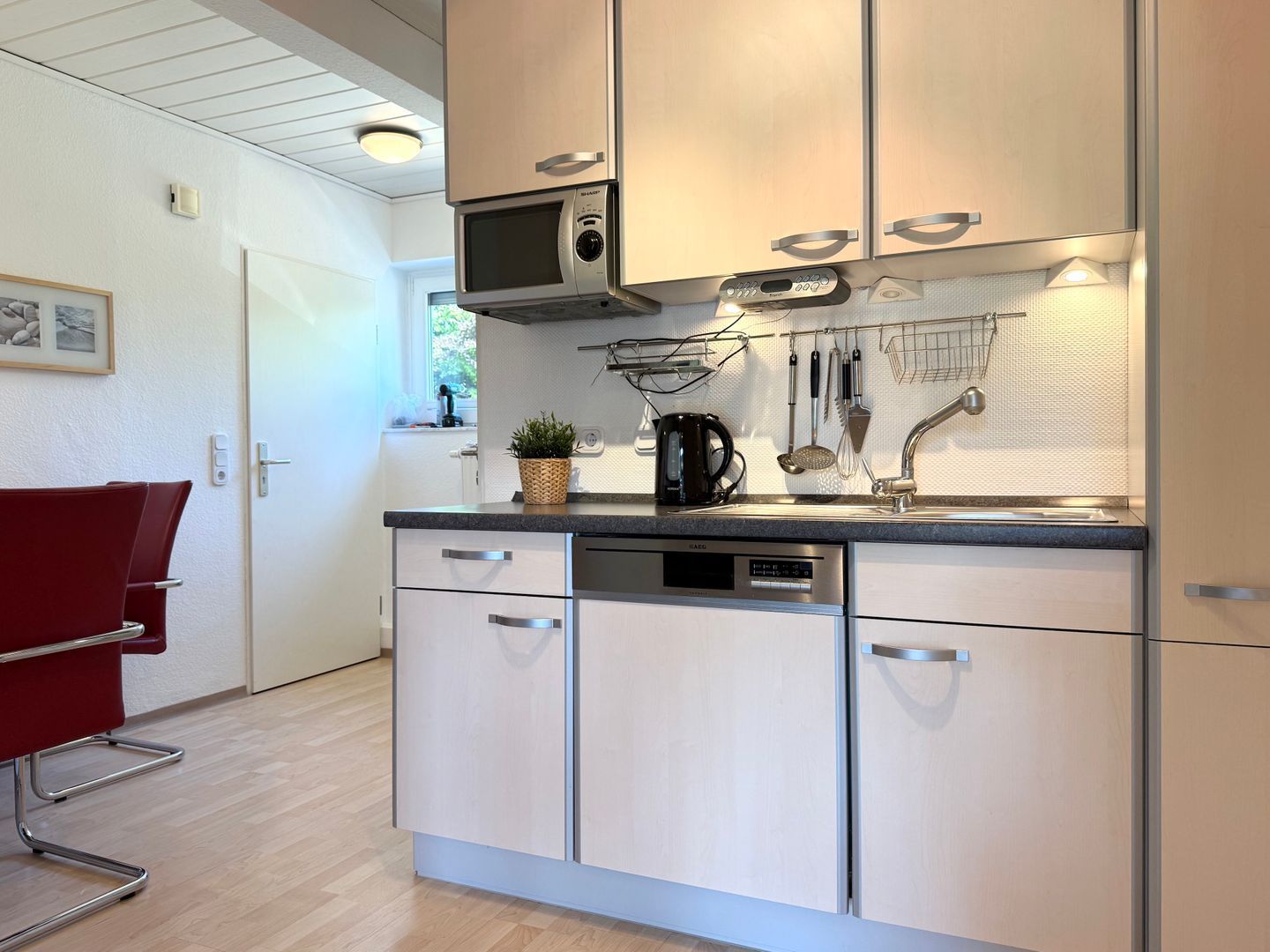 Una cocina moderna con electrodomésticos de acero inoxidable, cafetera y un colgador para utensilios.