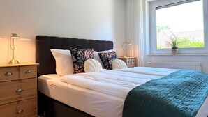 A bedroom with a bed, bedside tables, a window with a view, and a radiator.