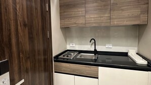 A modern kitchen with a black countertop, stainless steel sink, and wooden cabinets. - 106 AL-NAJEH JRE Apartments For Rent ave (Amman)
