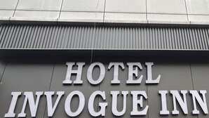 Un bâtiment portant l’enseigne « HOTEL INVOGUE INN », qui indique le nom de l’établissement.
