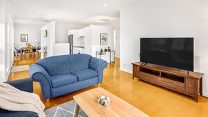 Una sala de estar moderna con un sofá azul, una unidad de entretenimiento de madera y un televisor de pantalla plana.