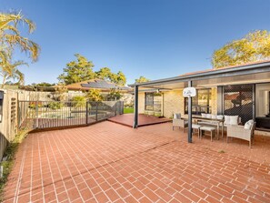 Eine Terrasse mit Pflasterboden, Gartenmöbeln und einem überdachten Sitzbereich.