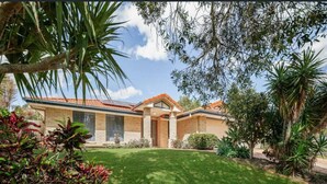 A modern house with a brick exterior, a red-tiled roof, and a well-maintained lawn.