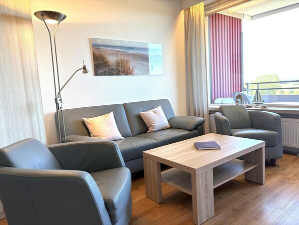 A modern living room with a grey sofa, a wooden coffee table, and a floor lamp. - Seabreeze - always a light sea breeze in your face! (Dahme)