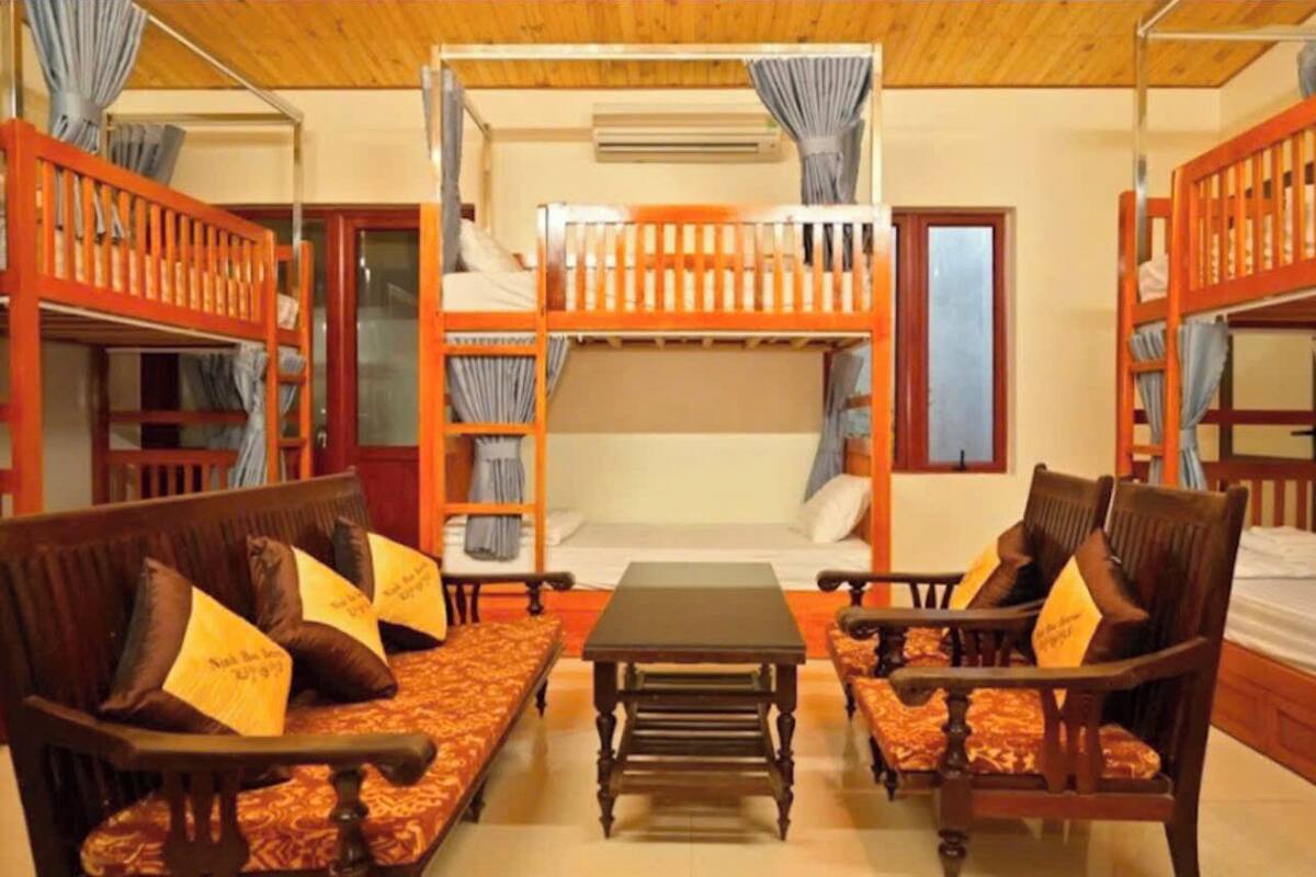 A room with bunk beds, a sofa, and a table.