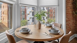 A round dining table with chairs, a vase with a plant, and dinnerware.