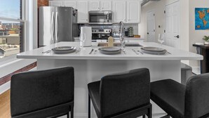 A modern kitchen with white cabinets, stainless steel appliances, and a central island with seating.