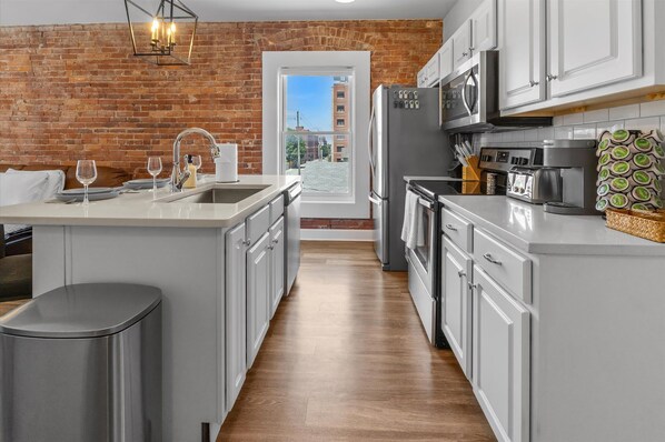 A modern kitchen with a brick wall, stainless steel appliances, and a view of the city.