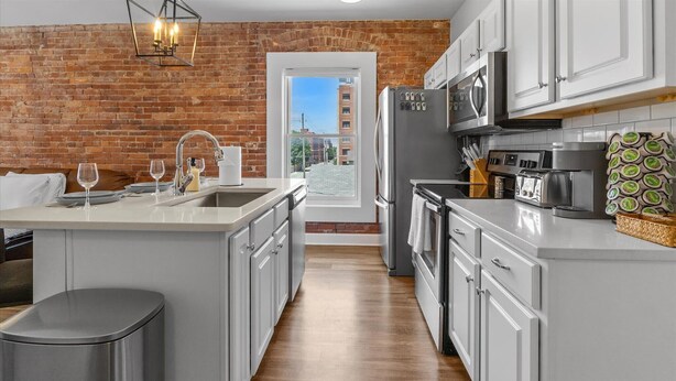 A modern kitchen with a brick wall, stainless steel appliances, and a view of the city.