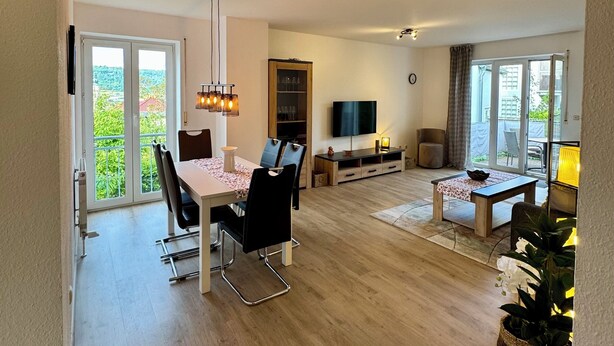 A spacious living area with a dining table, chairs, a TV, and a sofa.