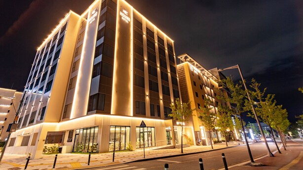 A modern hotel with a prominent entrance, large windows, and a well-lit facade. - HOUNDHOTELDAEGUHYUKSIN (Daegu)