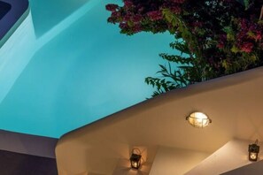 A modern building with a curved facade and a balcony. - Villa Historia – Timeless Luxury in the Heart of Oia (Santorini)