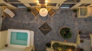 Un espace de détente avec un mur en pierre, un coin salon circulaire et une petite piscine.
