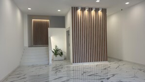 A modern interior with a marble floor, a staircase, and a vertical wooden panel wall.
