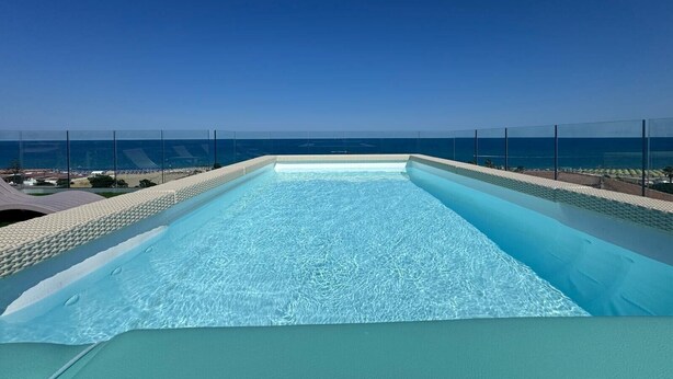 A rooftop infinity pool with a clear view of the ocean.