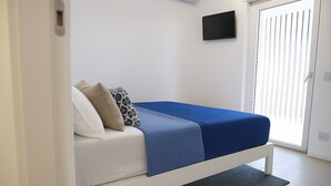 A modern bedroom with a white bed, blue bedding, and a grey rug.