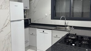 A modern kitchen with white cabinetry, a built-in dishwasher, a stove, and a window above the sink.